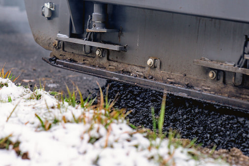 Maschine, die Asphalt einbaut, davor Schnee